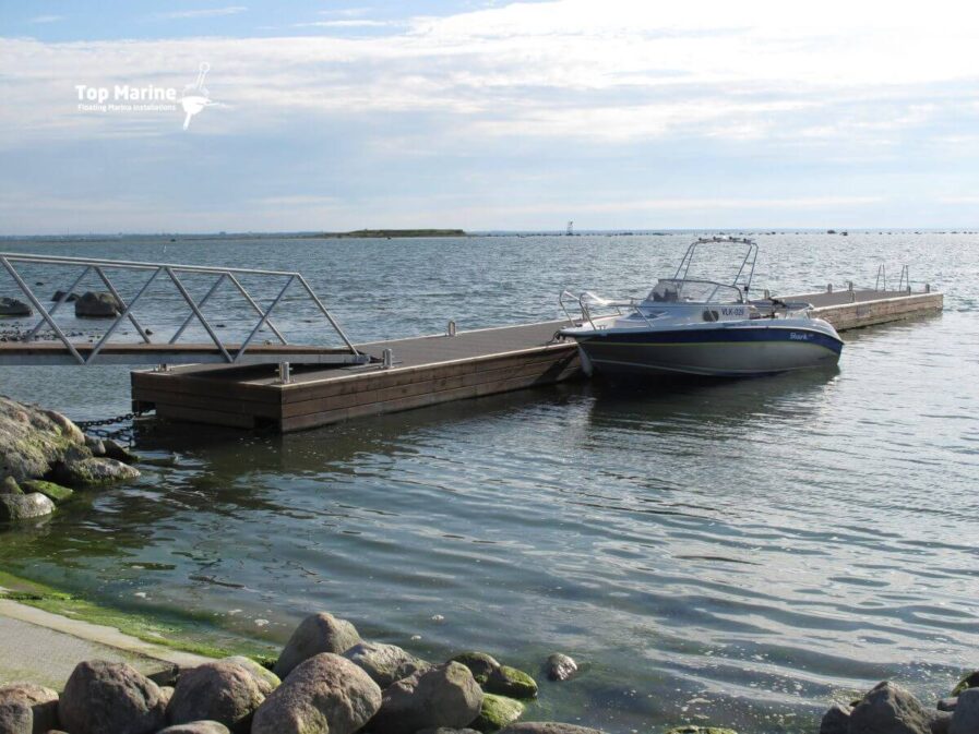 Flytbrygga med betongpontoner och båtplats vid kust