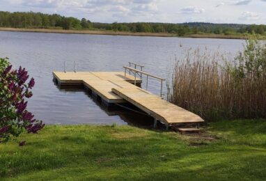 Badbrygga med plastflytkroppar vid sjöstrand