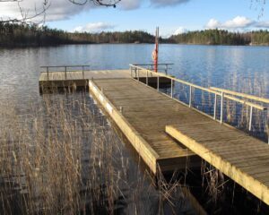 Trä- och betongbrygga med landgång vid lugnt vatten